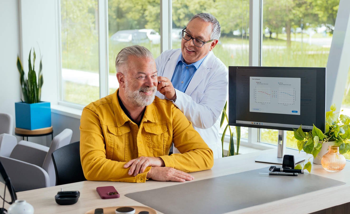 Man smiling being fit with hearing aids.