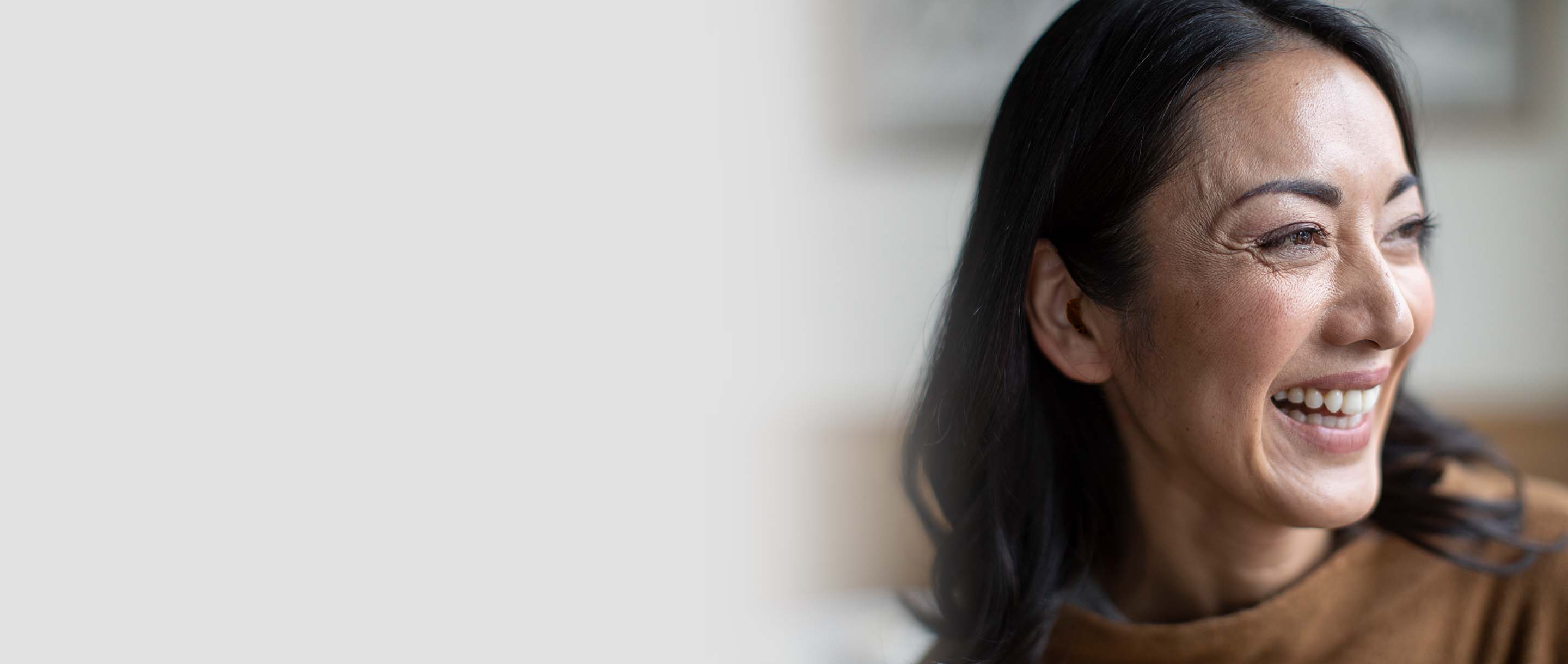 A woman smiling with a hearing aid in her ear
