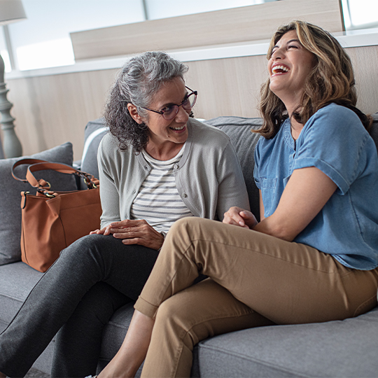 Two women sitting on coach laughing